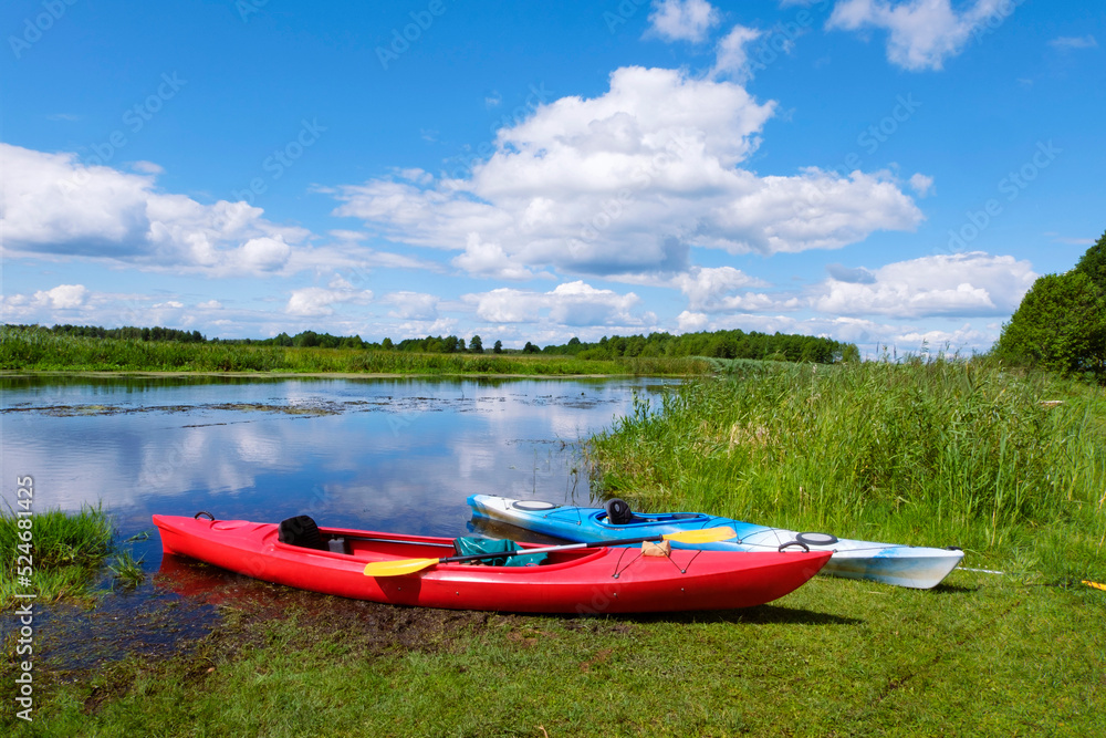 Two kayaks by the river bank. Scenic rural landscape of wild river, rafting along a river, water sport concept.