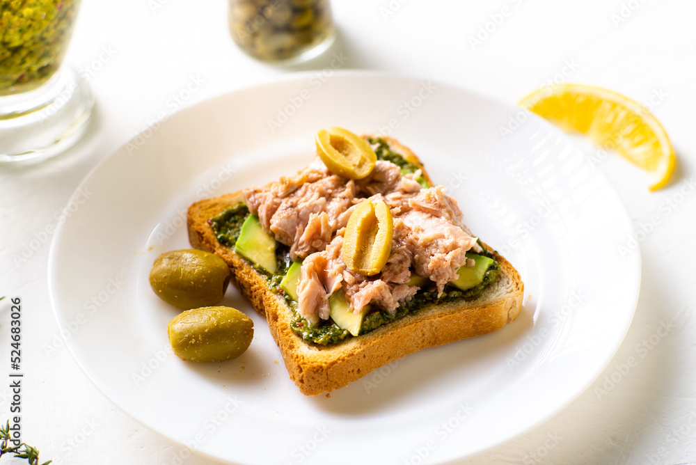 toast with tuna and avocado, olives with chimichurri sauce. On a white plate and white background. toast with tuna and avocado, olives with chimichurri sauce. On a white plate and white background.
