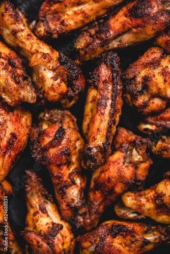 Close up of Roasted chicken wings on baking tray over dark background