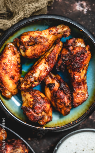Close up of Roasted chicken wings on rustic ceramic plate over dark background