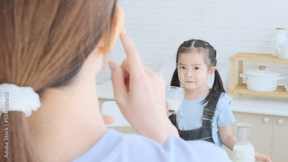 Cute asian daughter drinking milk with mother for take care in the kitchen. Cute asian daughter drinking milk with mother for take care in the kitchen.