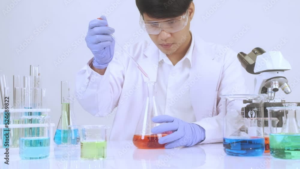 Scientist using dropper chemical liquid into test tube on table that have many beaker glasses and microscope at science laboratory. Scientist using dropper chemical liquid into test tube on table that have many beaker glasses and microscope at science laboratory.