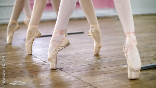 in ballet hall, Young ballerinas perform pas echappe in pointe shoes, goes up on toes, close-up. High quality photo