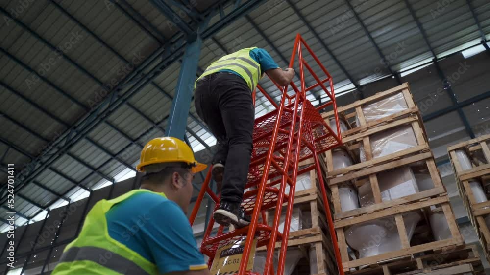 Vidéo Stock 4K, A worker working in a warehouse climbs the red ladder