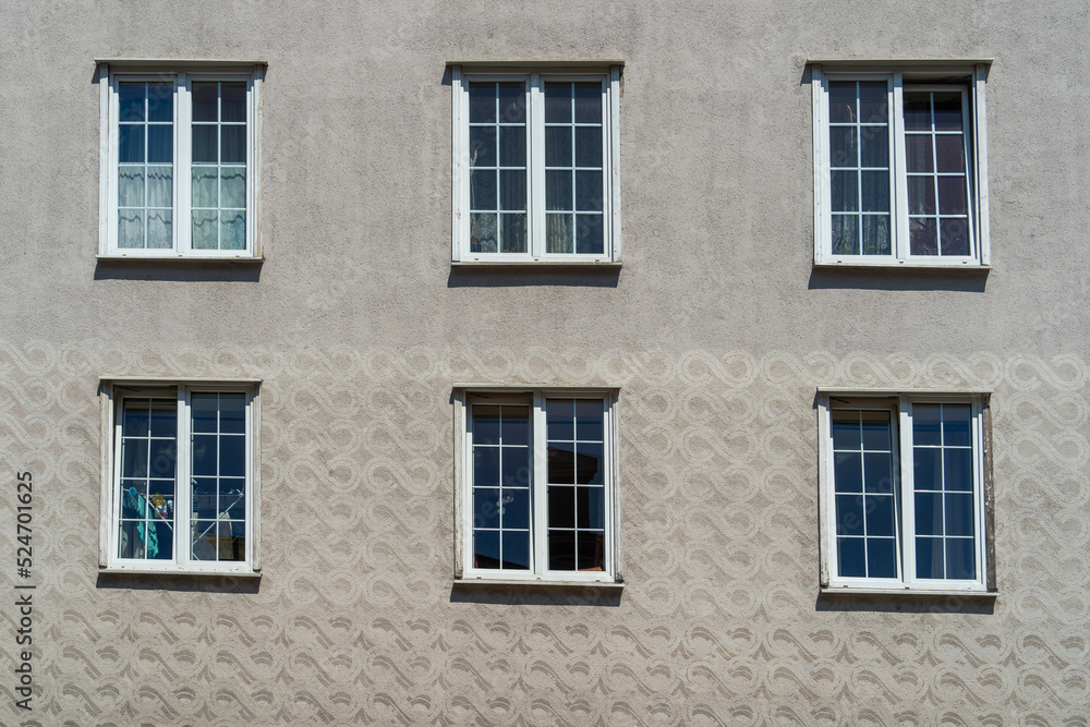Six windows with white wooden frames on a wall with gray 3D stucco on a sunny day in the historic center of Gdansk, Poland