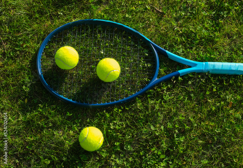 Tennis racket with balls on the grass