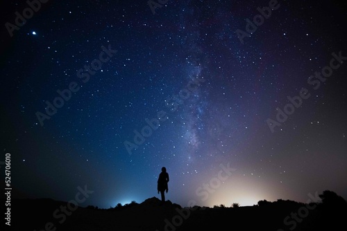 Milky Way. Night sky with stars and silhouette of a standing happy person with yellow and blue light. Space background, Astro photography 