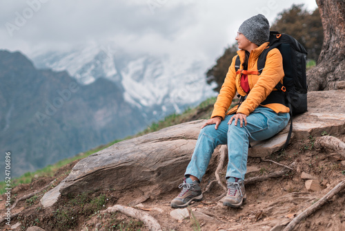 hiker in the mountains. Portrait of teenager girl hiker relaxing in mountains during Bhrigu Lake trek in Manali, India. Young Indian woman with backpack travelling. Wanderlust and travel concept.