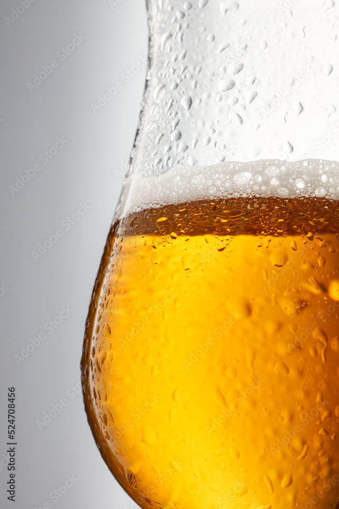 Detail of draught beer in glass. Glass of fresh and cold beer on gray background. Beer. Selective focus Detail of draught beer in glass. Glass of fresh and cold beer on gray background. Beer. Selective focus