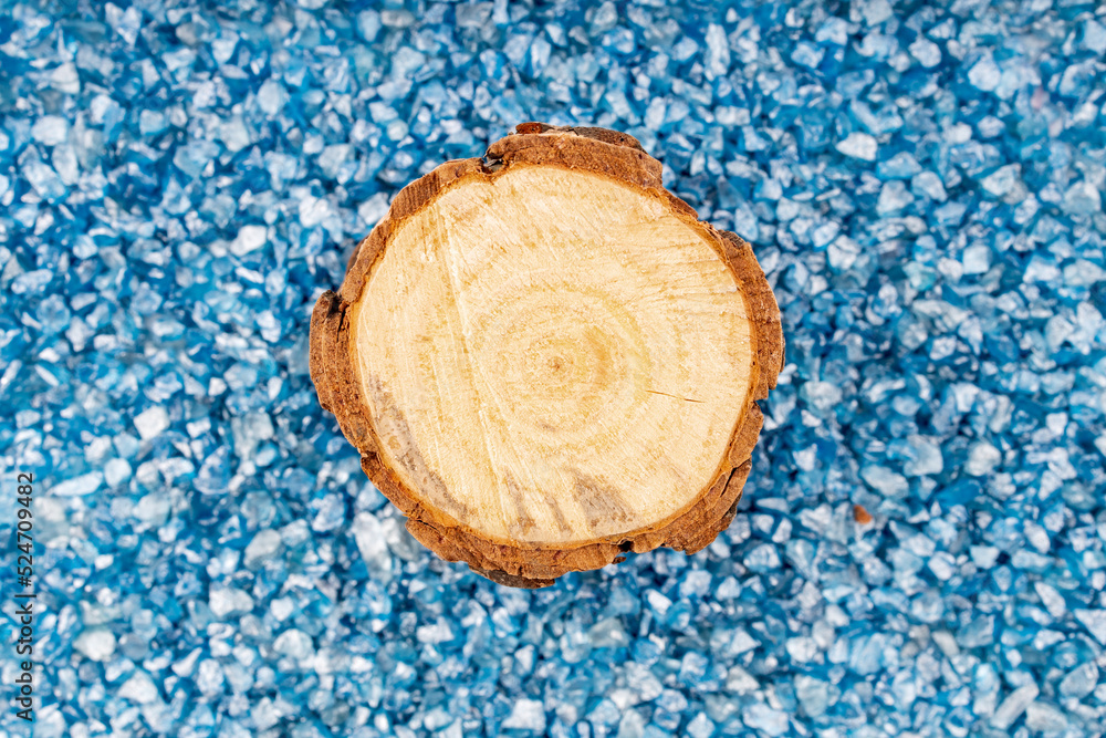 a background of blue stones in a continuous layer, on them is a round cut tree trunk, top view a background of blue stones in a continuous layer, on them is a round cut tree trunk, top view
