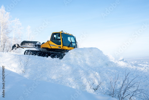 yellow tractor for leveling snow on the ski slope