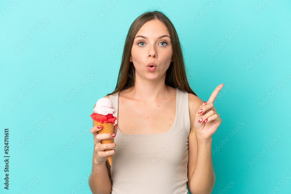 Young Lithuanian woman with cornet ice cream isolated on blue background intending to realizes the solution while lifting a finger up Young Lithuanian woman with cornet ice cream isolated on blue background intending to realizes the solution while lifting a finger up