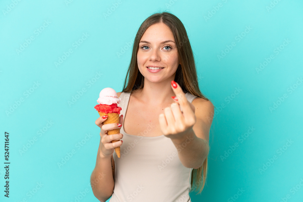 Young Lithuanian woman with cornet ice cream isolated on blue background doing coming gesture Young Lithuanian woman with cornet ice cream isolated on blue background doing coming gesture