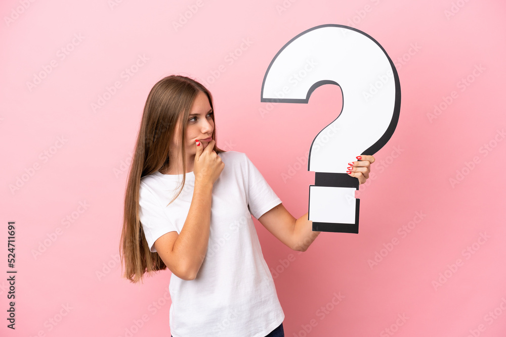 Young Lithuanian woman isolated on pink background holding a question mark icon and having doubts Young Lithuanian woman isolated on pink background holding a question mark icon and having doubts