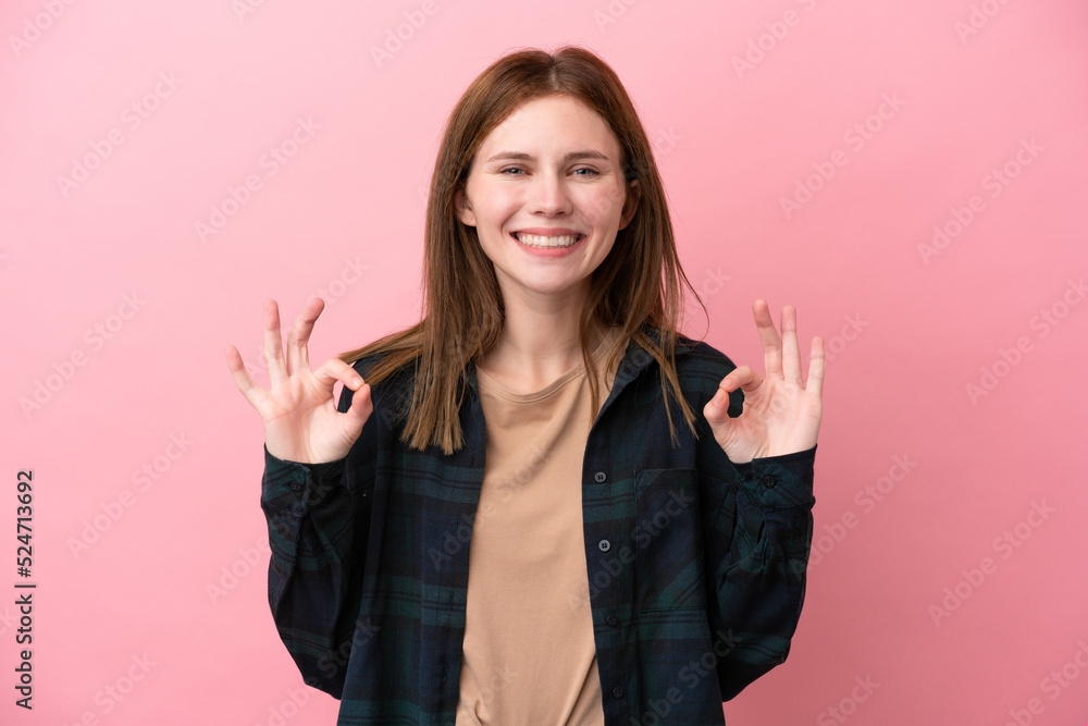 Young English woman isolated on pink background showing ok sign with two hands Young English woman isolated on pink background showing ok sign with two hands