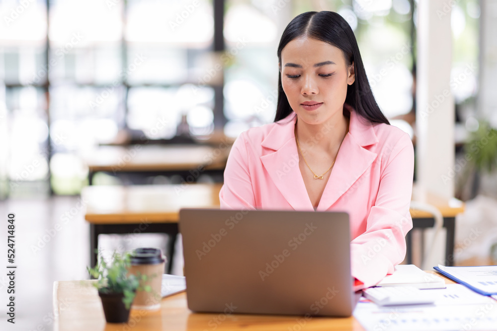 Asian Businesswoman Using a laptop computer and working at office with calculator document on desk, doing planning analyzing the financial report, business plan investment, finance analysis concept. Asian Businesswoman Using a laptop computer and working at office with calculator document on desk, doing planning analyzing the financial report, business plan investment, finance analysis concept.