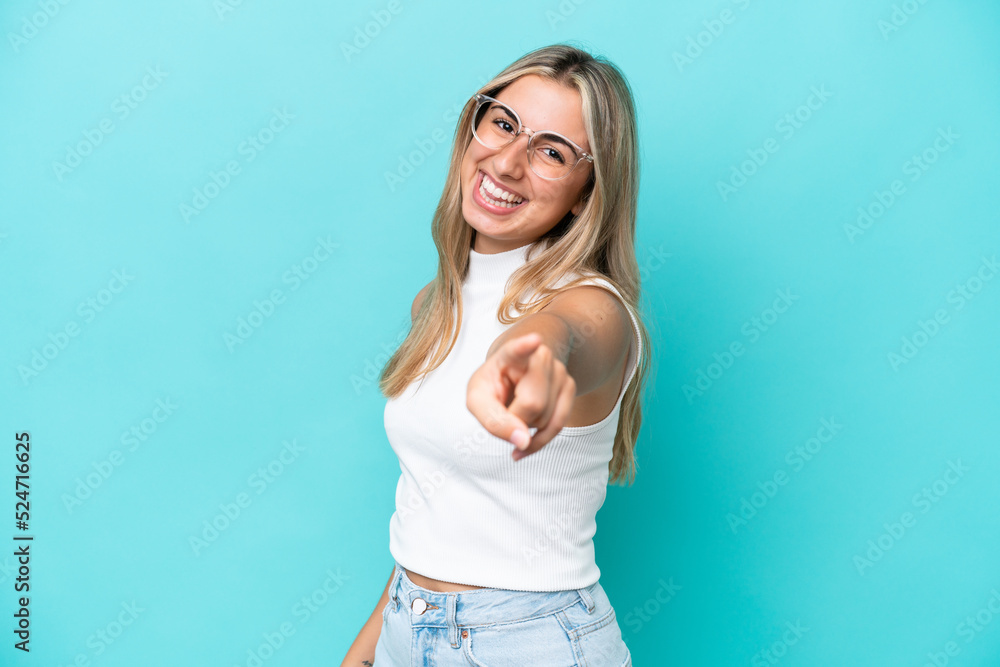 Young caucasian woman isolated on blue background pointing front with happy expression Young caucasian woman isolated on blue background pointing front with happy expression