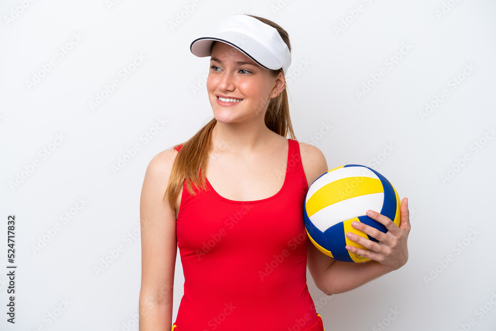 Young caucasian woman playing volleyball isolated on white background looking to the side and smiling