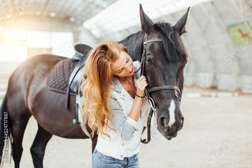 Photographie beautiful blond professional female jockey standing near horse