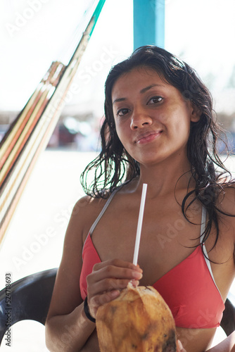 young latin woman with dark skin drinking coco water