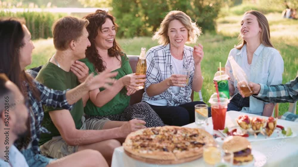 Group of friends are relaxing together outdoor. Young people are sitting at the table, having fun talking and eating food. Group of friends are relaxing together outdoor. Young people are sitting at the table, having fun talking and eating food.