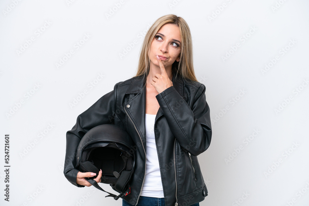 Pretty blonde woman with a motorcycle helmet isolated on white background having doubts while looking up Pretty blonde woman with a motorcycle helmet isolated on white background having doubts while looking up