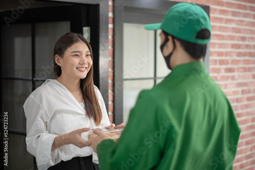 Young Asian woman picked up the package from delivery man rider ware green uniform with smile feeling happy. online shopping and food delivery concept