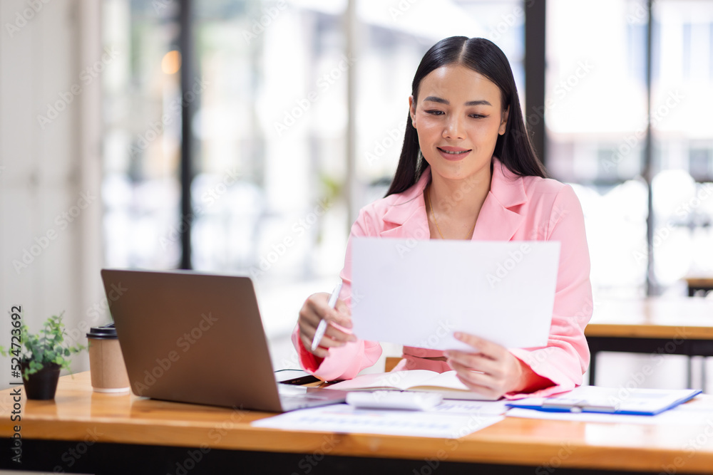 Business Asian woman working in the workplace with documents on her desk, doing planning analyzing the financial report, business plan investment, finance analysis concept Business Asian woman working in the workplace with documents on her desk, doing planning analyzing the financial report, business plan investment, finance analysis concept