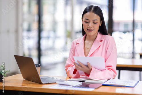 Business Asian woman working in the workplace with documents on her desk, doing planning analyzing the financial report, business plan investment, finance analysis concept	
