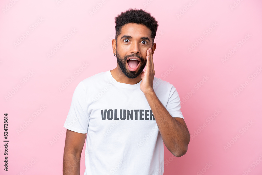 Young volunteer man isolated on pink background with surprise and shocked facial expression Young volunteer man isolated on pink background with surprise and shocked facial expression