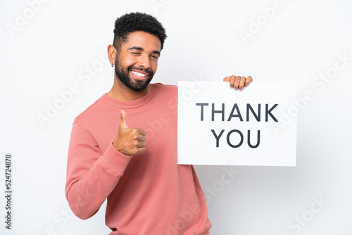 Young Brazilian man isolated on white background holding a placard with text THANK YOU and pointing to the front