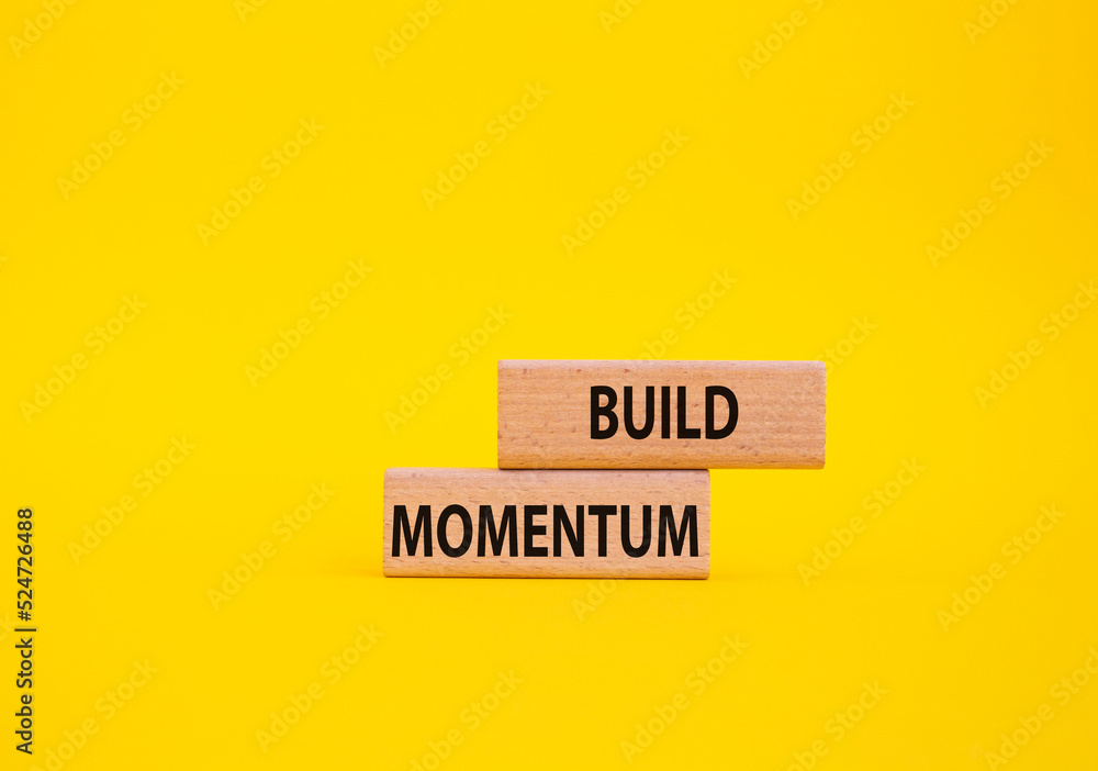 Build momentum symbol. Wooden blocks with words Build momentum. Beautiful yellow background. Business and Build momentum concept. Copy space. Build momentum symbol. Wooden blocks with words Build momentum. Beautiful yellow background. Business and Build momentum concept. Copy space.