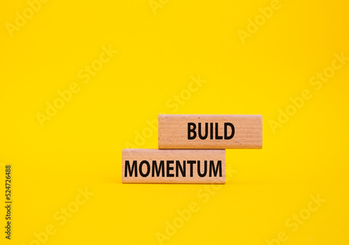 Build momentum symbol. Wooden blocks with words Build momentum. Beautiful yellow background. Business and Build momentum concept. Copy space.