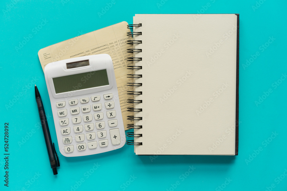 close up top view on blank book with pen and calculator and backing account on teal background for add content about business and economy concept close up top view on blank book with pen and calculator and backing account on teal background for add content about business and economy concept