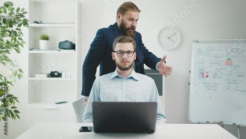 Mature angry screaming boss man dissatisfied by employee work result. Furious businessman harass stressed worker in bright office photo