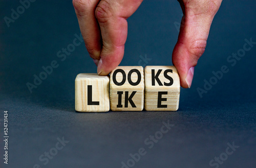 Looks like symbol. Concept words Looks like on wooden cubes. Businessman hand. Beautiful grey table grey background. Business, popular quotes and looks like concept. Copy space.
