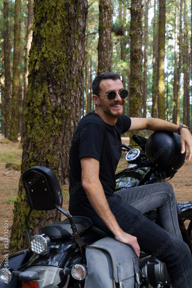retrato a motero en el bosque subido en moto custom