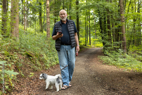 man is checking smartphone on a dog walk