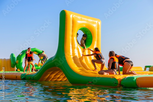 Inflatable bounce castle floating in water.Aqua park for children having fun in water park.Aquapark with attractions in the sea. photo