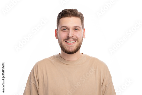 Happy caucasian male with bristle in stylish sweater standing indoors with sincere smile. Portrait of young joyful man expressing positive emotions in studio. © MYDAYcontent