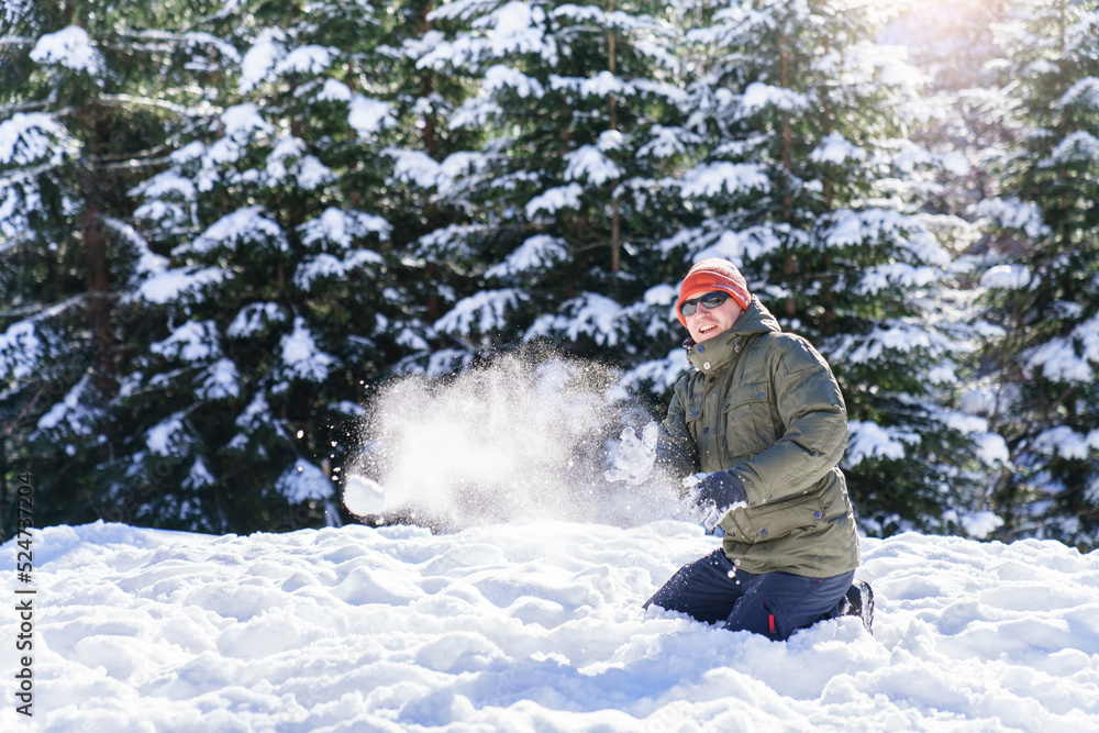 Snowball fight. Young man playing in snow in winter and having fun in snowy forest. Family outdoors activities on Christmas holidays. Authentic lifestyle moment