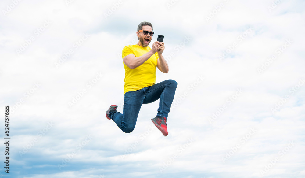 man jumping and chatting on phone on sky background man jumping and chatting on phone on sky background