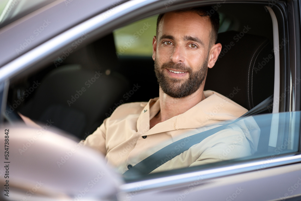Portrait of confident smiling latin man driving a car looking at camera. Car sharing concept Portrait of confident smiling latin man driving a car looking at camera. Car sharing concept