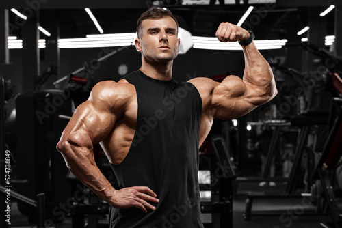 Foto Muscular man in gym showing biceps muscles. Strong male