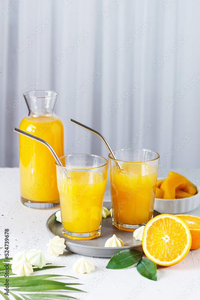 Glasses with orange juice, orange slices and mango on a gray background. Glasses with orange juice, orange slices and mango on a gray background.