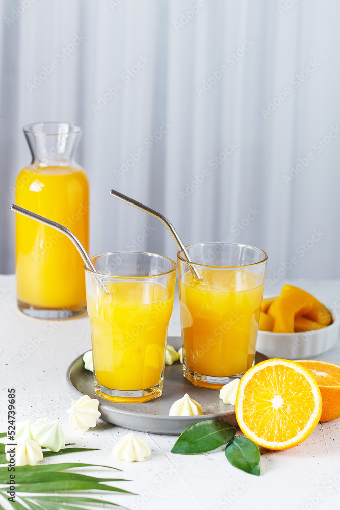 Glasses with orange juice, orange slices and mango on a gray background. Glasses with orange juice, orange slices and mango on a gray background.