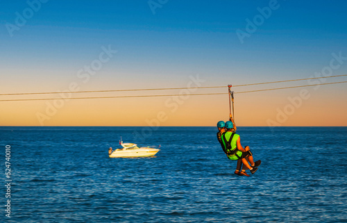 Zipline is an exciting adventure activity .Man and woman hanging on a rope-way.Tourists ride on the Zipline through the ocean on Bournemouth, England