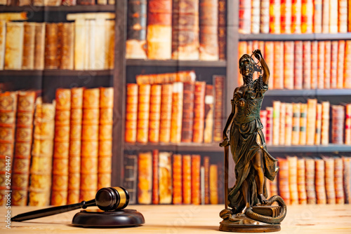 Lawyer office. Statue of Justice, scales and Judge's gavel against the backdrop of a wall of books or a library . Legal law, advice and justice concept