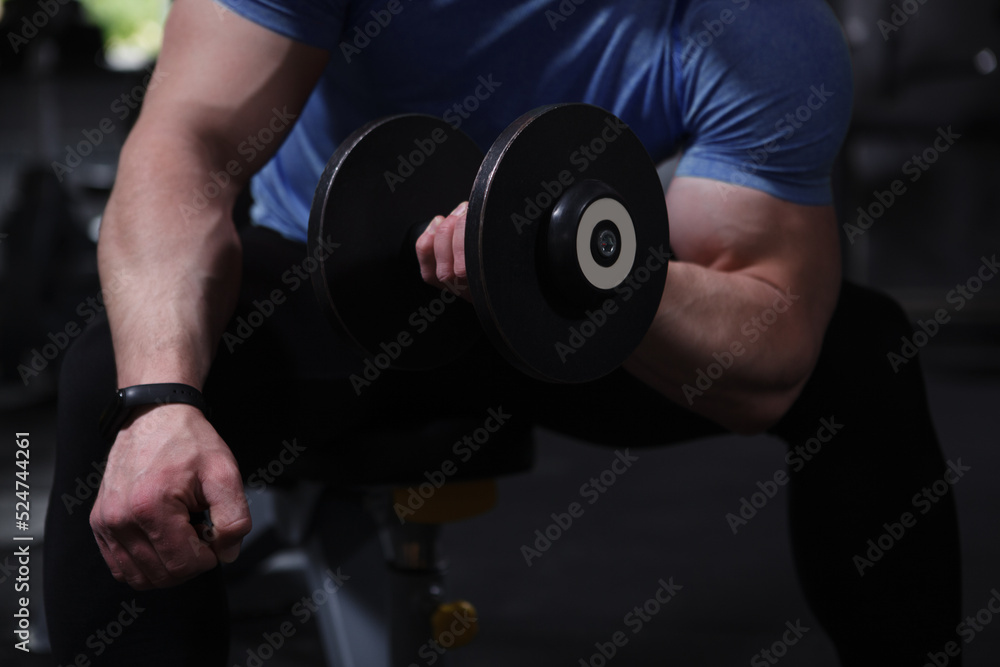 Cropped close up of a heavy dumbbell in hand of muscular bodybuilder Cropped close up of a heavy dumbbell in hand of muscular bodybuilder