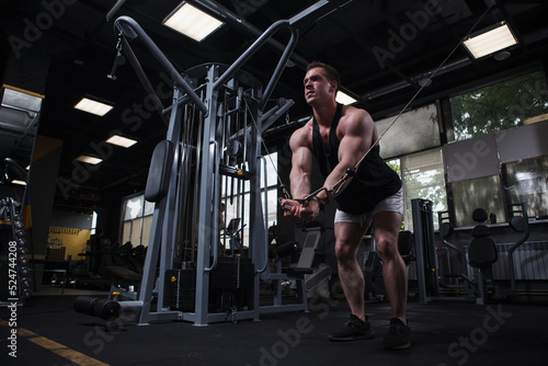 Ripped young bodybuilder doing chest cable crossover exercise at the gym, copy space